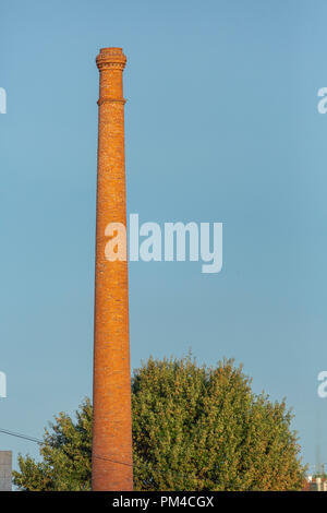 Chimney industrial ceramic brick orange, with tree and blue sky as background Stock Photo