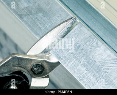 Cutting steel stud with tin snip cutter Stock Photo