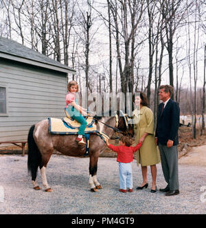 President John F Kennedy with his wife, First Lady Jacqueline Bouvier Kennedy, as their daughter, Caroline, sits atop a pony and their son, John Jr. holds his arms out, 1963  (Photo courtesy of JFK Library)  File Reference # 1003 107THA Stock Photo