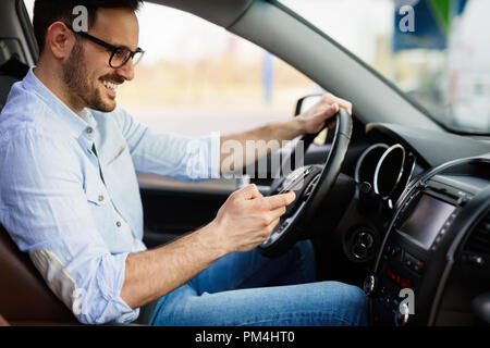 Man looking at mobile phone while driving Stock Photo