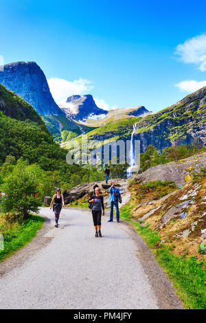 Norway, Olden - August 1, 2018: People at pathway to Briksdal or Briksdalsbreen glacier with green mountains, snow and waterfall Stock Photo