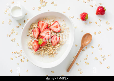 Oatmeal porridge with strawberries and milk in bowl on white background. Top view. Healthy breakfast, vegetarian lifestyle concept Stock Photo