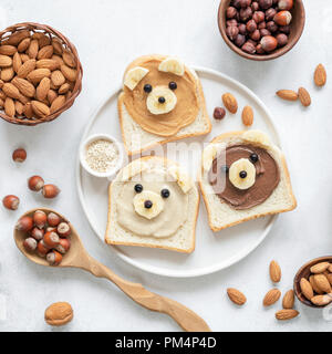 Nut butter toast in shape of cute funny bear for kids served on a white plate. Top view. Creative food art, breakfast for kids, school lunch concept Stock Photo