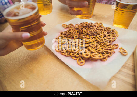 beer and pretzels. Perfect for Octoberfest. Natural wooden background. Front view with female and male hands Stock Photo