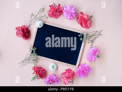 black chalk board with fresh carnation flower on soft cream background with copy space Stock Photo