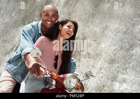Romantic Relationship. Young diverse couple riding bike on the city street together smiling happy Stock Photo