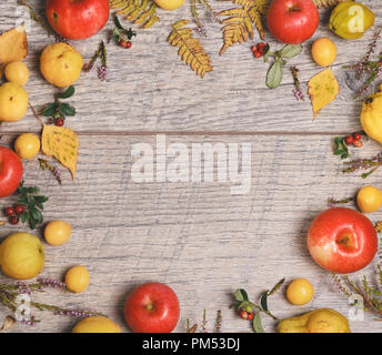 Wreath made of autumn leaves, berries, apples and nuts on wooden background. Autumn concept. Stock Photo