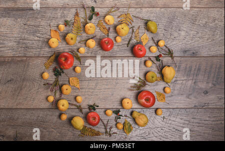 Wreath made of autumn leaves, berries, apples and nuts on wooden background. Autumn concept. Stock Photo