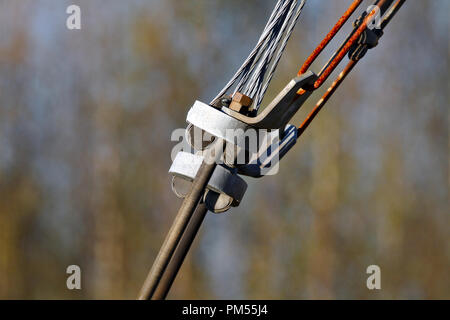 Old connection. Close photo of rusty tensioner of power lines. A threader rod connected to steele cables. Isolated from dark brown background Stock Photo