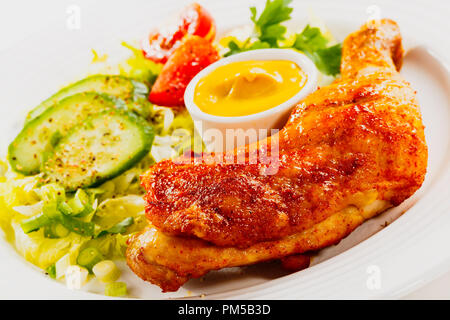 isolated roasted chicken leags with fresh vegetables on white plate Stock Photo
