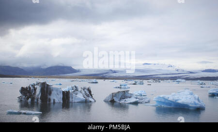 Icebergs drifting off in the Jökulsárlón glacier lagoon off the calving face of Breiðamerkurjökull on a gloomy day. Stock Photo