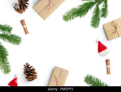 Merry Christmas layout composition, top view with xmas presents, cinnamon sticks, fir tree branches and pine cones on a white background. Stock Photo