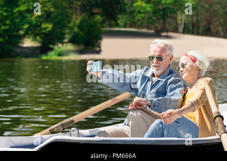 Progressive pensioners taking selfies while rowing and relaxing Stock Photo