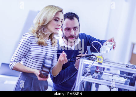 Concentrated workers checking work of 3D printer Stock Photo