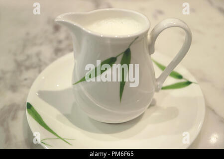 Closed up white with green pattern ceramic milk pitcher on white marble table Stock Photo