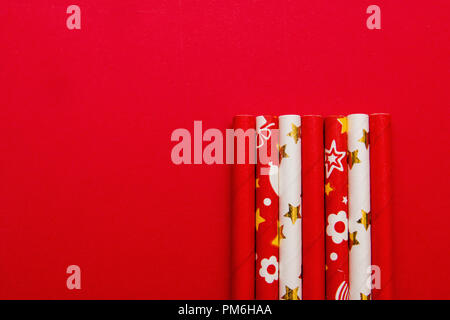 several red and white straws on a red background with copy space. Stock Photo