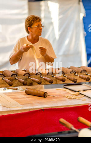 CERVIA (RA), ITALY - SEPTEMBER 16, 2018: woman preparing Hungarian Chimney cakes at European Market, street exhibition of typical products and flavour Stock Photo