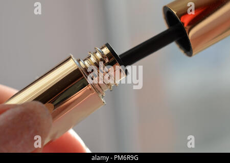 woman hand with finger holds professionall tool black lash mascara brush closeup Stock Photo