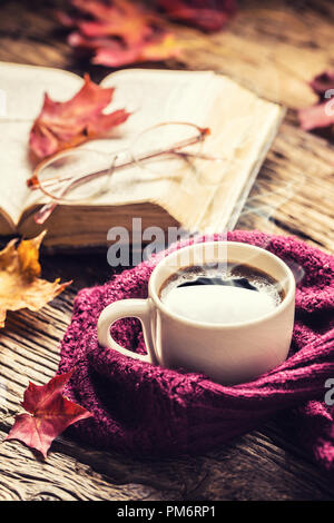 Cup of coffee old  book  glasses and autumn leaves on rustic wooden table. Stock Photo