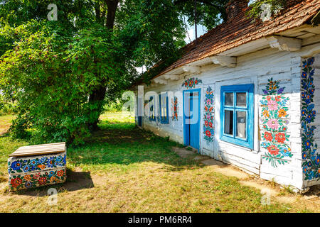 Zalipie, Poland, August 19, 2018:  Colourful house with flowers painted on walls and sundial in the village of Zalipie, Poland. It is known for a loca Stock Photo