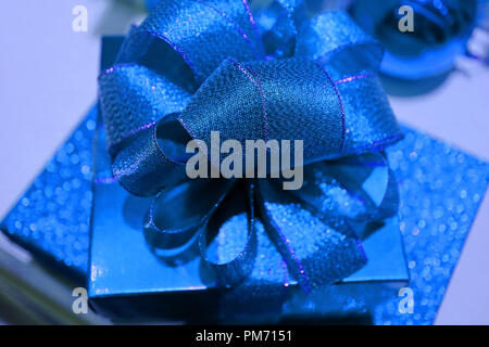 Closed up Shiny Royal Blue Square Shaped Gift Box with Gritter Blue Ribbon Bow, Selective Focus and Blurred Background Stock Photo