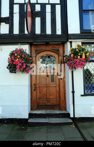 Wooden door surrounded by hanging basket of flowers on half timbered building in Market Street, Rye, East Sussex, UK Stock Photo