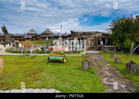 Chopped hut and cart on wooden wheels on the background of a two-story log cabin Stock Photo