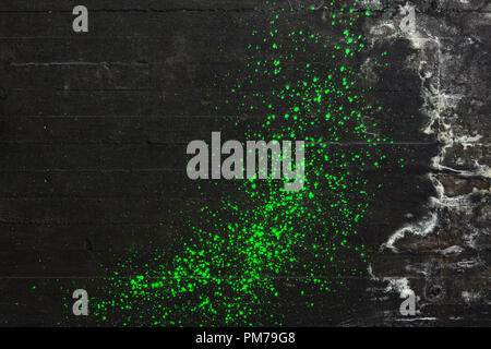 Green pain splatter on black concrete wall Stock Photo
