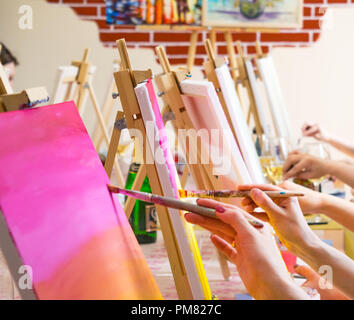 Many women of different ages drawing on canvases with brushes during masterclass in the art studio, hands only Stock Photo