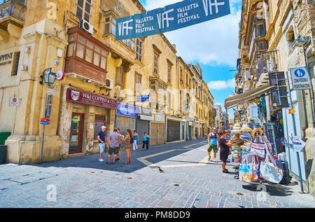 VALLETTA, MALTA - JUNE 17, 2018: The souvenir shops, boutiques, workshops and cafes line historical Merchants street with preserved medieval edifices, Stock Photo