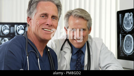 Senior doctors sitting at desk smiling Stock Photo