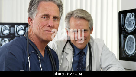 Mature doctors sitting at desk smiling Stock Photo