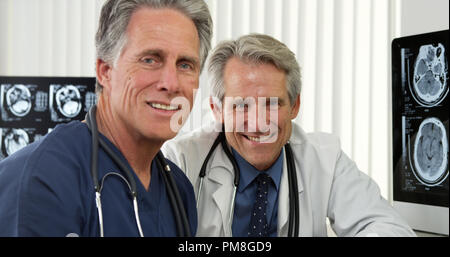 Senior doctors sitting at desk smiling Stock Photo