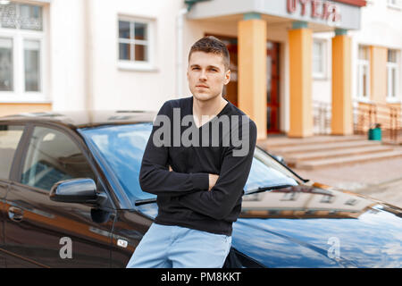 Handsome stylish man in black shirt and blue pants near the car Stock Photo