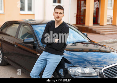 handsome man in a black T-shirt near the car Stock Photo