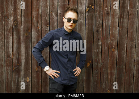 Young man in sunglasses near a vintage wooden wall Stock Photo