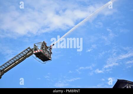 Firefighters seen on a crane extinguishing a blaze that broke out at a hotel building. A massive fire erupted at a local hotel here in Srinagar on Saturday, but there was no loss of life or injury according to police. Fire tenders were rushed to the spot and police, and fire and emergency services were trying to douse the flames. Stock Photo