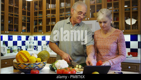 Senior couple using tablet computer in kitchen during lunch Stock Photo
