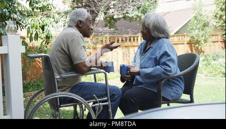 Disabled elderly African man talking with wife in the backyard Stock Photo