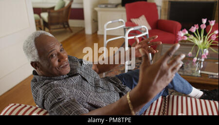 Senior African man talking on a couch Stock Photo