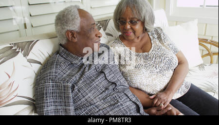 Happy retired black couple sitting on a couch Stock Photo