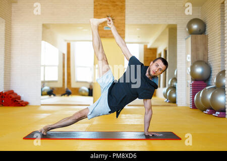 Young man practicing yoga in the gym Stock Photo