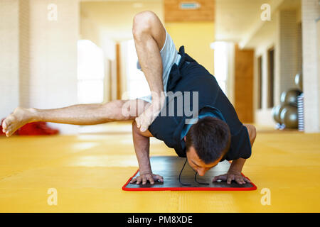 Young man practicing yoga  or hand standing pose on yoga mat in the gym Stock Photo