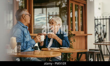 Senior couple talking over a cup of coffee at cafe. Old man and woman sitting at coffee shop having a conversation while having coffee. Stock Photo