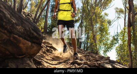 Low section of trail runner running on challenging rocky terrain. Male runner's legs working out on extreme terrain outdoors. Stock Photo