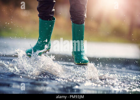 Child walking in wellies in puddle on rainy weather Stock Photo