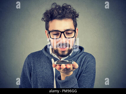 Hipster man using a smart phone voice recognition function isolated on wall background Stock Photo