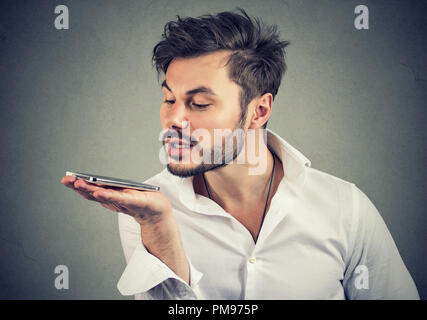 Hipster man using a smart phone voice recognition function isolated on wall background Stock Photo