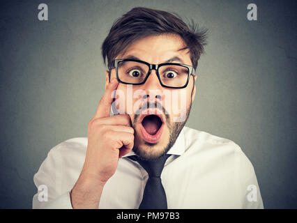 Young formal man in eyeglasses looking excited with clear vision on gray background Stock Photo