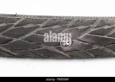 A beaten bicycle tire in the workshop. A bicycle wheel pierced with a nail. Light background. Stock Photo